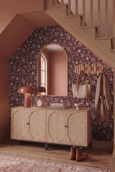 Eingangsbereich mit Blumentapete, Sideboard mit Wiener Geflecht, Bogenwandspiegel und Holztreppe.