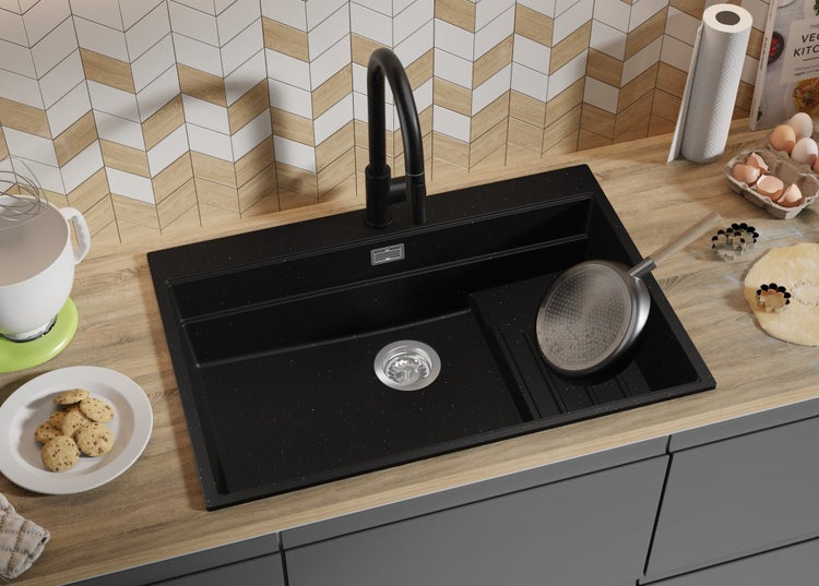 Schwarze Küchenspüle mit Abtropffläche und schwarzer Armatur auf einer Küchentheke