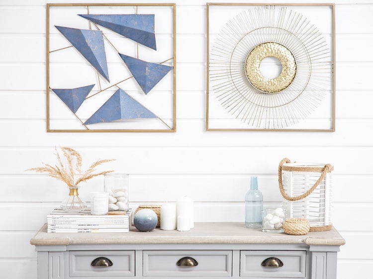 Dekoratives Interieur mit geometrischer Wandkunst, Trockenblumen und Kerzen auf einem grauen Schrank