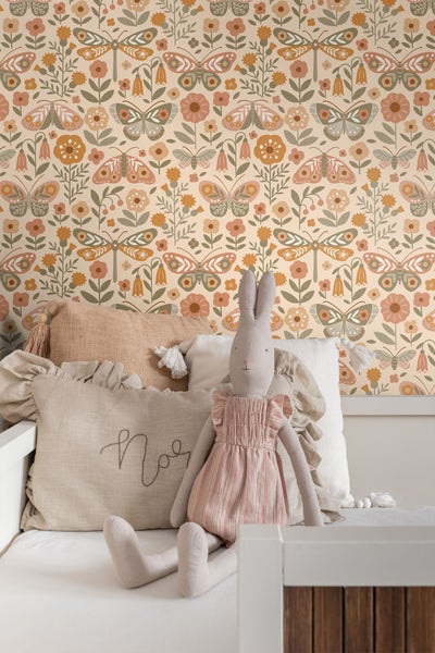Tapete mit Blumen-, Schmetterlings- und Libellenmuster im Retro-Stil hinter einem Bett mit Kissen und Stofftier