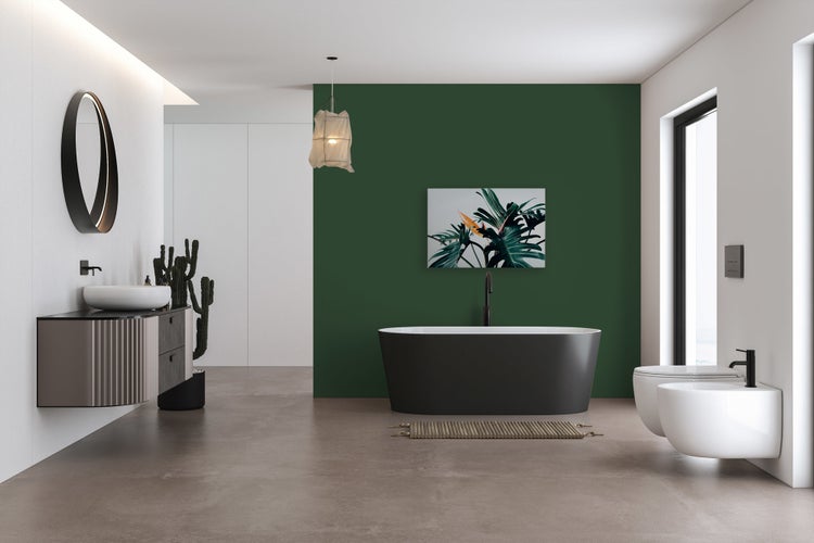 Modernes Badezimmer mit dunkler freistehender Badewanne, wandhängendem Waschtisch, hängendem WC und Bidet vor einer dunkelgrünen Akzentwand.