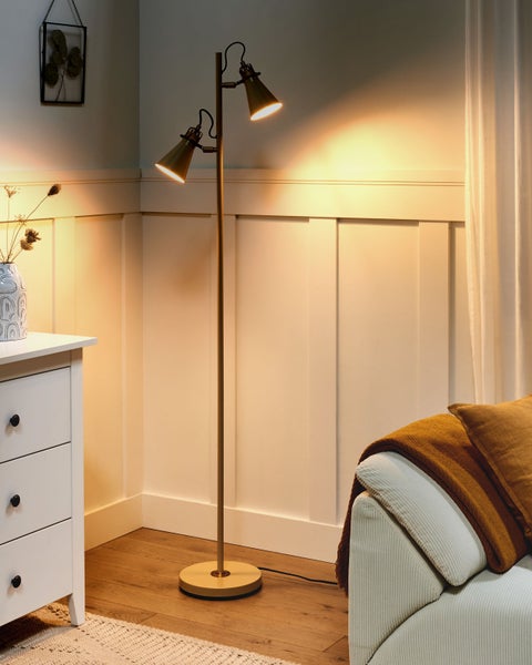 Stehlampe mit zwei Lampenschirmen im Wohnzimmer neben Kommode und Sofa