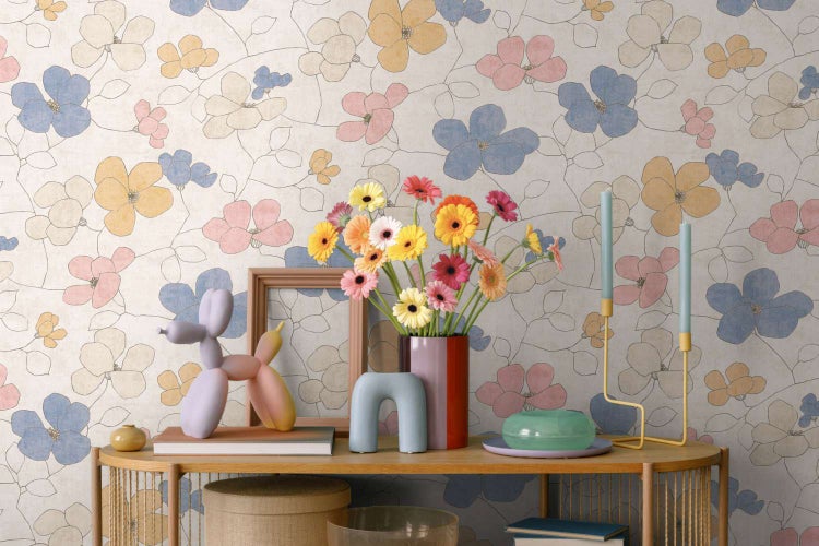 Vliestapete mit floralem Blumenmuster, angebracht in einem Wohnbereich mit Dekoration auf einem Holztisch.