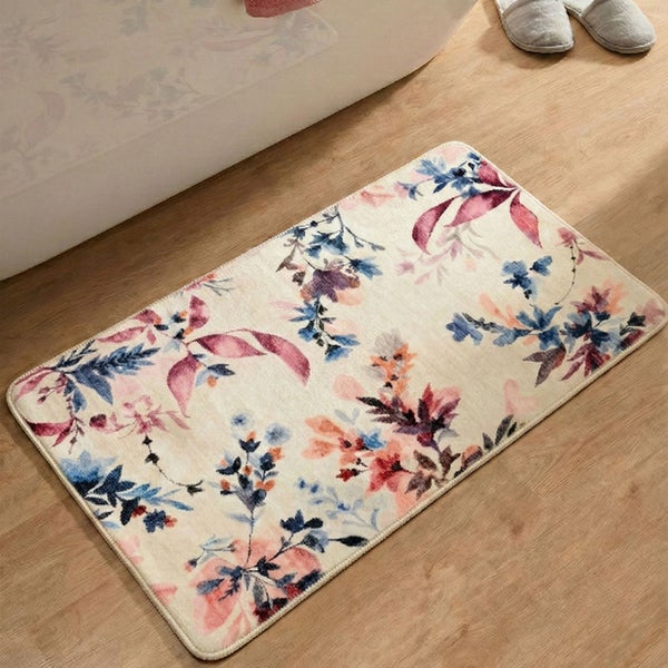 Rechteckige Badematte mit floralem Muster auf hellem Grund, liegend auf einem Holzboden neben einer Badewanne.