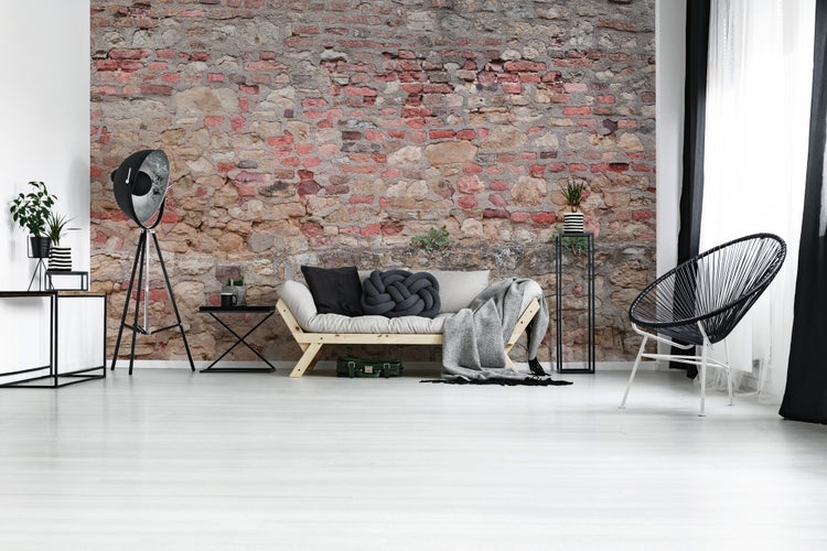 Modernes Wohnzimmer mit Fototapete in Backstein- und Natursteinoptik, hellem Boden und Möbeln im Industrial-Stil.