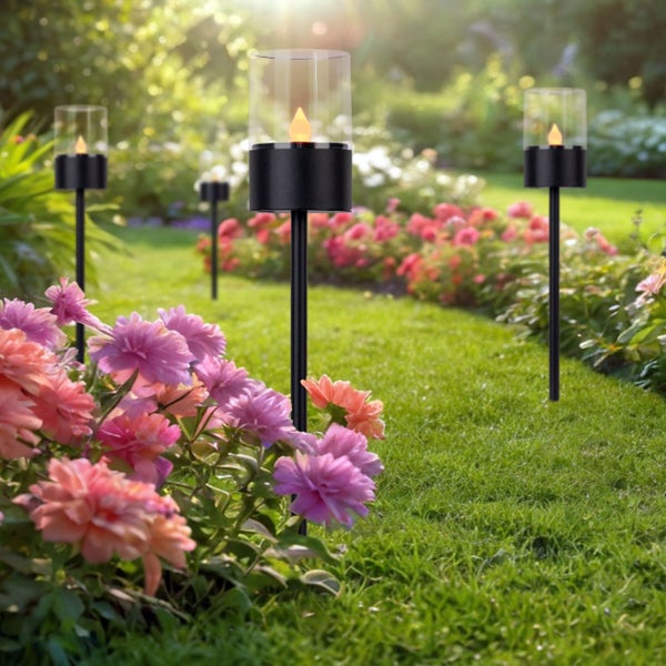 Gartenansicht mit mehreren Solarleuchten mit Flammeneffekt zwischen Blumenbeeten