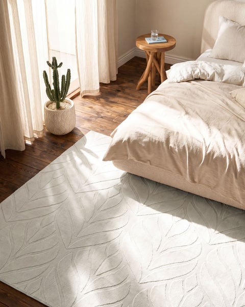 Hochflorteppich mit geprägtem Blattmuster in einem hellen Schlafzimmer mit Echtholzboden und Bett.
