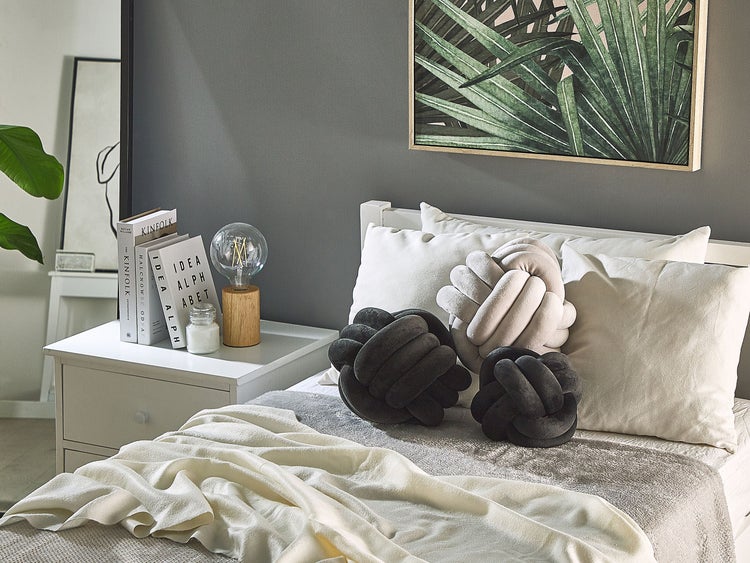 Schlafzimmer mit Bett, Kissen und Dekorationen auf einem Nachttisch