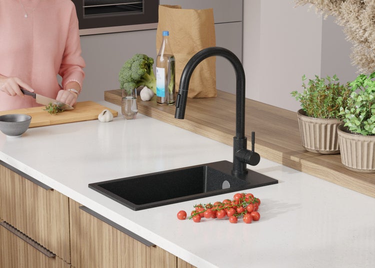 Küchenszene mit schwarzem Spülbecken und Armatur, ergänzt durch Lebensmittel und Küchenutensilien.