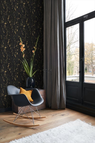 Wohnzimmer mit gemusterter Tapete, Schaukelstuhl und Vorhängen für die Fensterdekoration.