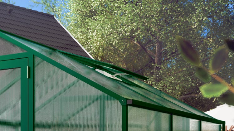 Gewächshaus mit grünem Aluminiumrahmen, Hohlkammerplatten und einem leicht geöffneten Dachfenster in einem Garten.