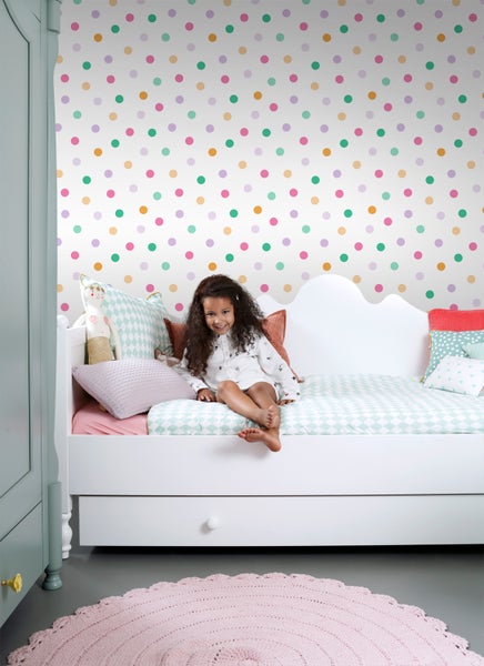 Mädchenzimmer mit Bett, gemusterter Tapete und rundem Teppich