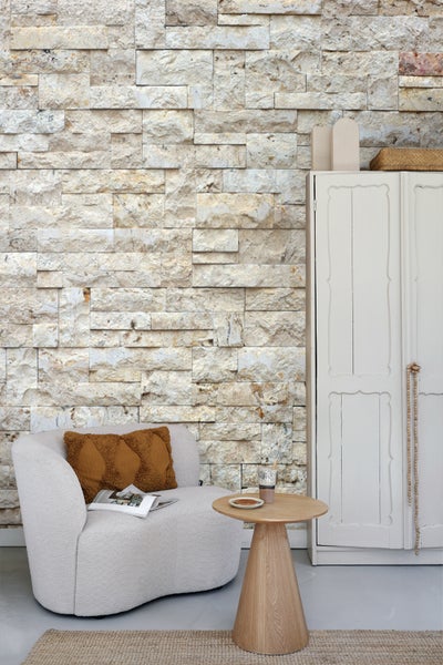 Wohnzimmer mit Sessel, Beistelltisch und Steinwand