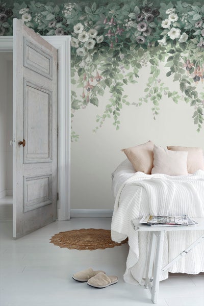 Helles Schlafzimmer mit floraler Tapete, Bett, Nachttisch und geöffneter Tür