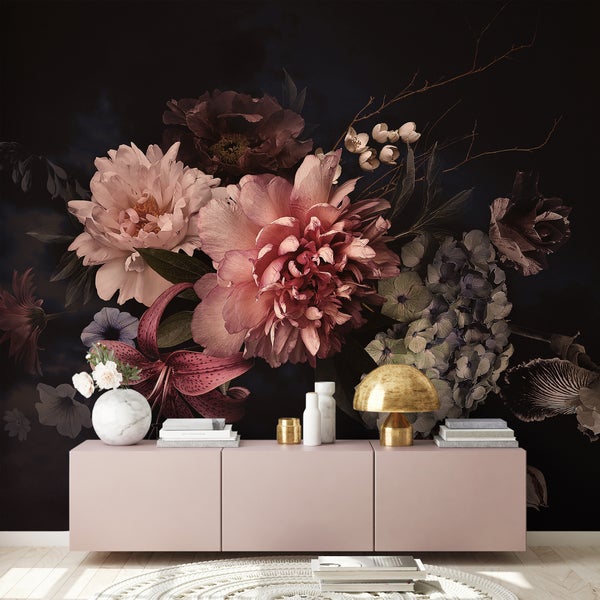 Fototapete mit großen Blumenmotiven wie Pfingstrosen auf dunklem Hintergrund hinter einem rosa Sideboard in einem modern eingerichteten Raum.