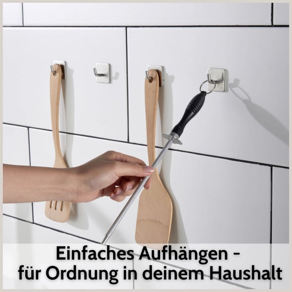 Selbstklebende Wandhaken aus Edelstahl an einer Kachelwand montiert, zum Aufhängen von Küchenutensilien und einem Wetzstahl.