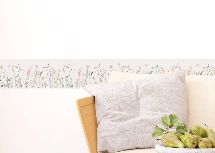 Selbstklebende Tapetenbordüre mit Blumenwiesen-Motiv in einem hellen Schlafzimmer über einem Nachttisch und Bett.