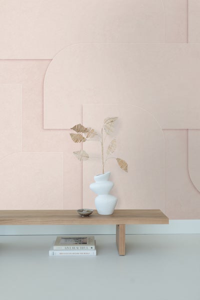 Szene mit einer Vase und Trockenblumen auf einem Holztisch vor einer geometrischen Tapete