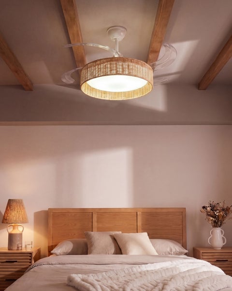 Deckenventilator mit integrierter LED Beleuchtung und Rattanschirm in einem Schlafzimmer mit Holzbalkendecke.
