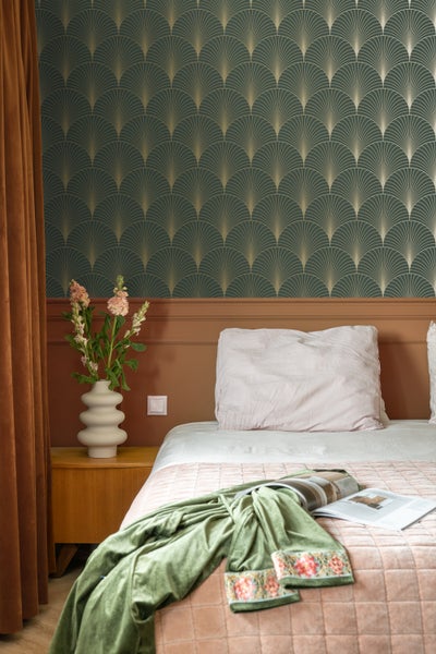 Schlafzimmer mit gemusterten Tapeten, Bett und Nachttisch