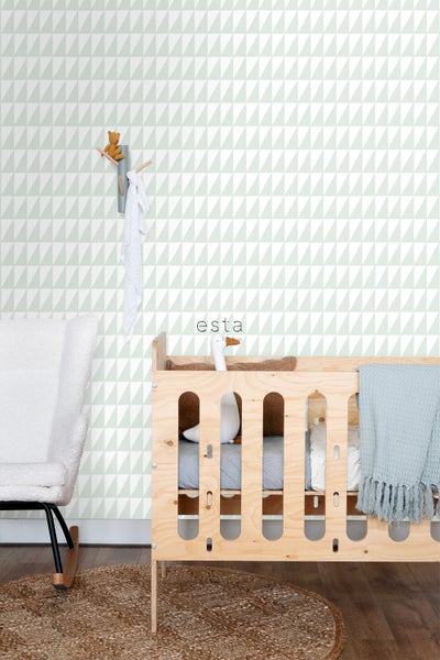 Kinderzimmer mit geometrischer Tapete, Babybett aus Holz und Schaukelstuhl