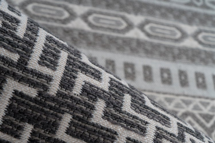 Nahaufnahme eines Flachgewebe-Teppichs für innen und außen mit geometrischem Muster und strukturierter Oberfläche.