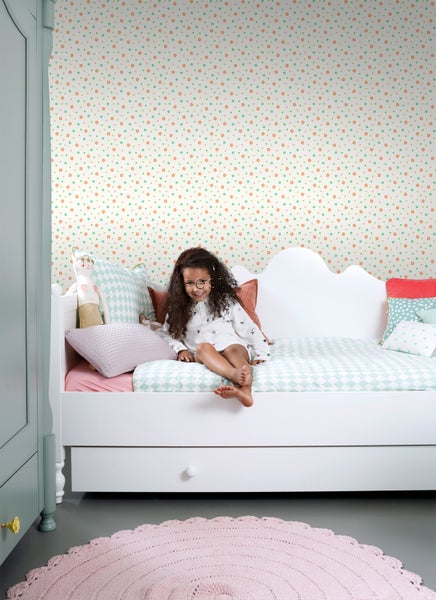 Helles Kinderzimmer mit gemusterter Tapete, Bett, Mädchen und Teppich