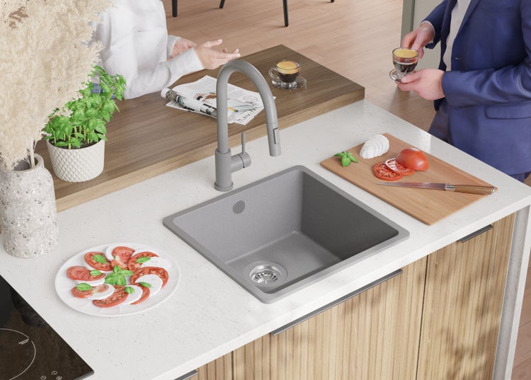 Küchenszene mit Spüle, Armatur, Lebensmitteln und zwei Personen.