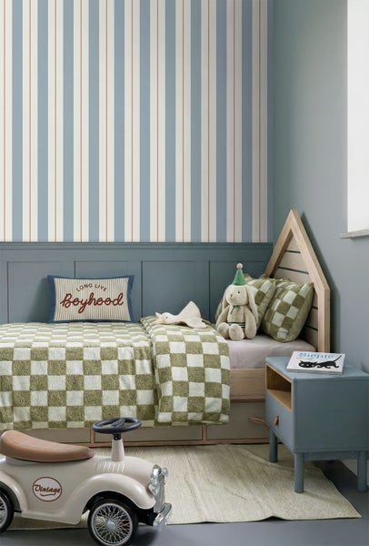 Kinderzimmer mit gestreifter Tapete in Blau, Weiß und Rot, einem Hausbett mit karierter Bettwäsche und einem blau-grauen Nachttisch.