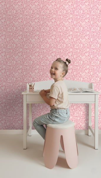Mädchen am Schreibtisch vor rosafarbener Blumentapete