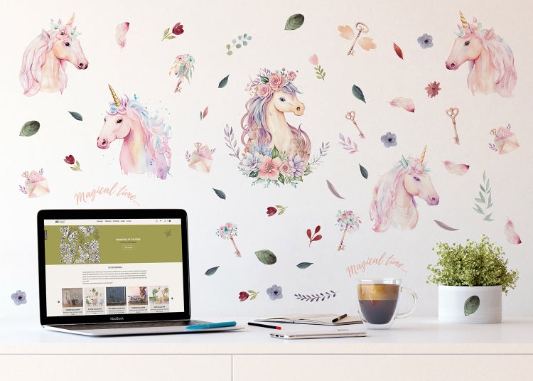 Wandtattoo-Set mit Aquarell-Illustrationen von Einhörnern und Blumen in einer hellen Raumszene mit Schreibtisch und Laptop.