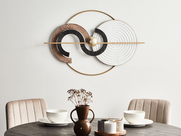 Dekoratives Wandobjekt aus Metall über einem Esstisch mit Gedecken und Dekorationen.