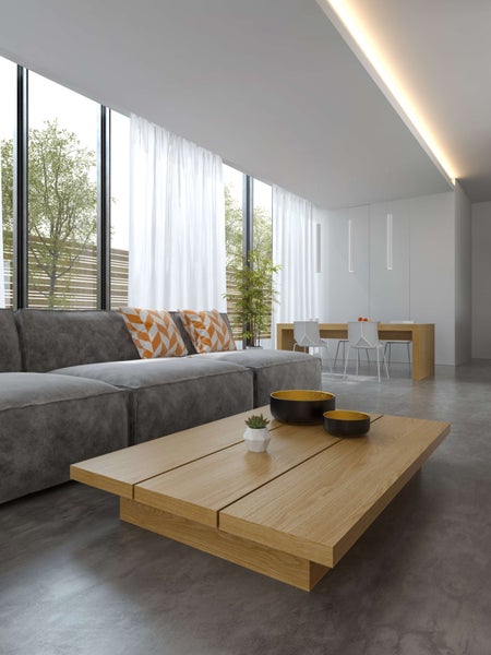 Helles Wohnzimmer mit Couch, Holztisch und großen Fenstern.