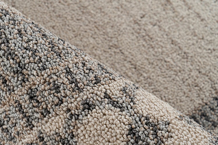 Nahaufnahme eines Teppichbodens mit Schlingenstruktur und Muster in Beige und Dunkelgrau.