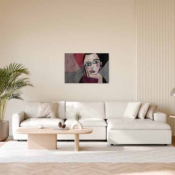 Wohnzimmer mit Sofa, Tisch und einem Wandbild mit einem abstrakten Frauenporträt.