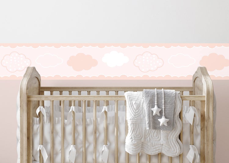 Selbstklebende Bordüre mit Wolkenmuster in einem hellen Kinderzimmer über einem hölzernen Gitterbett.
