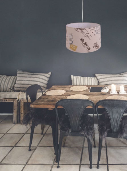 Esszimmer mit Holztisch, Stühlen und Hängelampe mit Postkartenmotiv