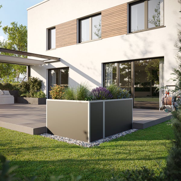 Moderner, dunkelgrauer Pflanzkasten auf einer Holzterrasse vor einem weißen Wohnhaus mit Rasenfläche und Bepflanzung.