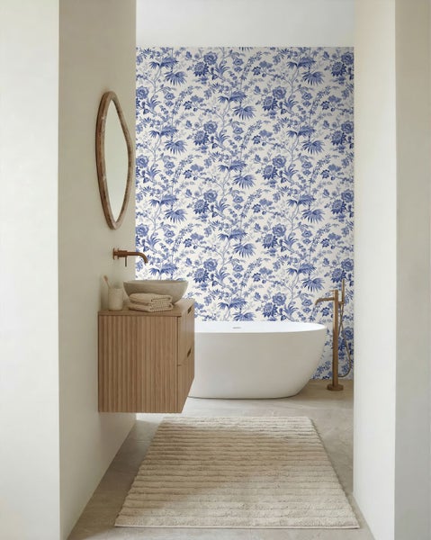 Modernes Badezimmer mit blau-weißer Mustertapete, freistehender Badewanne und hölzernem Waschtischunterschrank.