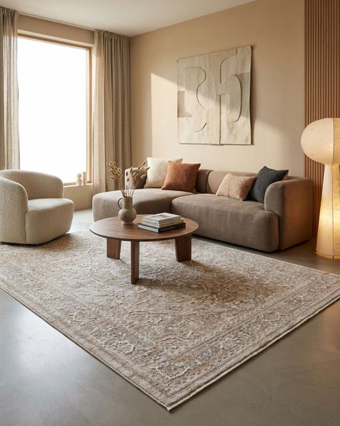 Modernes Wohnzimmer mit großem, gemustertem Teppich im Vintage-Stil, braunem Ecksofa, rundem Couchtisch aus Holz und einem Sessel.