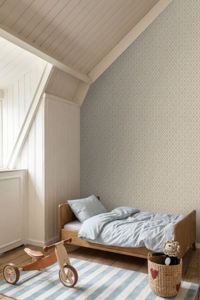 Helles Kinderzimmer im Dachgeschoss mit gemusterter Tapete, Holzbett mit gestreifter Bettwäsche, Holz-Laufrad und gestreiftem Teppich.