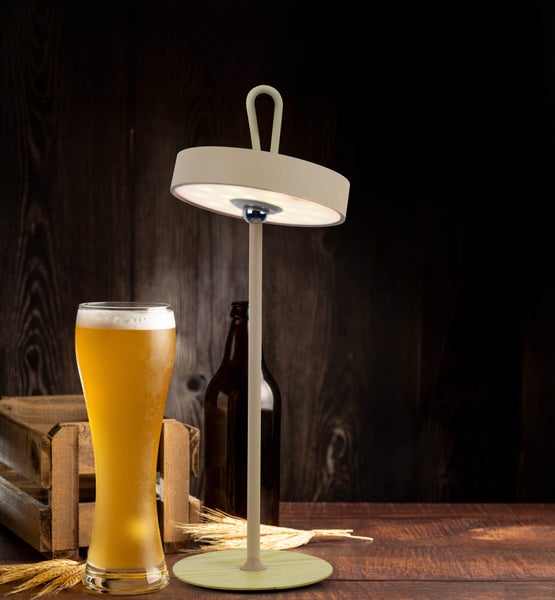 Dekorative Stehleuchte neben Glas und Flasche Bier auf einem Holztisch