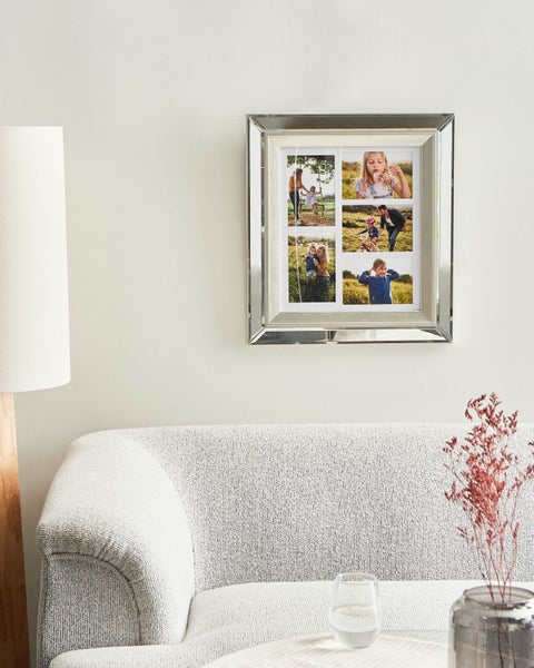 Collage-Fotorahmen mit Spiegelrand an der Wand über einem Sofa.