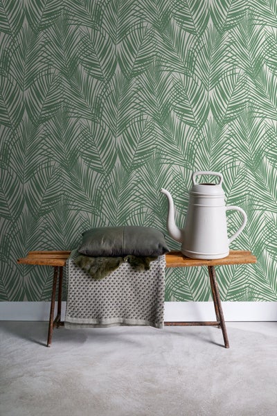 Wohnraum mit Palmenblattmuster-Tapete, einer Bank, einem Kissen und einer Gießkanne