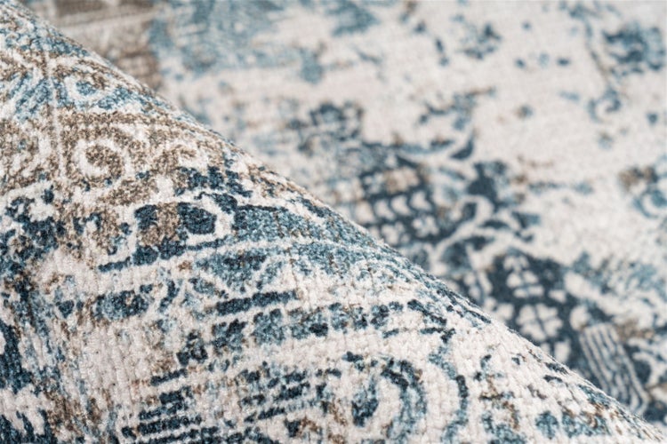 Nahaufnahme eines Teppichs mit Vintage-Muster in Blau und Beige, weiche Oberfläche mit kurzem Flor.