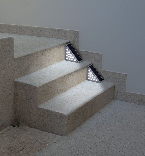 Zwei dreieckige Solar-Treppenleuchten auf einer Steintreppe.