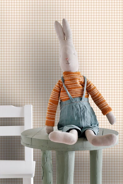Dekoratives Stofftierhase mit Overall auf kleinem Tisch