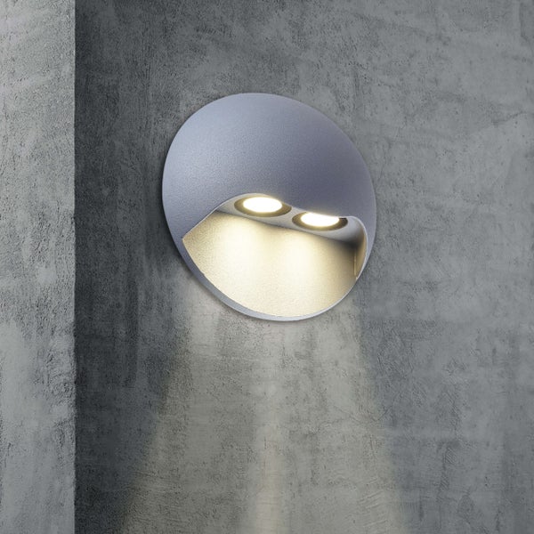 Runde Wandleuchte für den Aussenbereich mit zwei Lichtquellen an einer grauen Wand