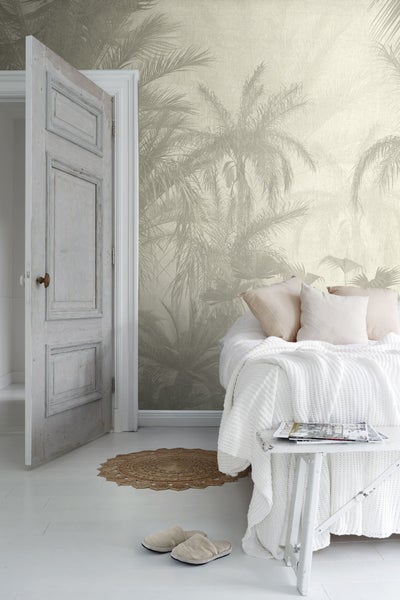 Wohnraum mit Palmenmuster-Tapete, Bett und Tür