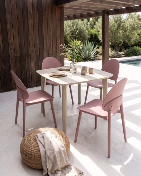 Modernes Gartenmöbel-Set mit quadratischem Esstisch und vier rosa Stühlen auf einer hellen Terrasse unter einer Pergola neben einem Pool.
